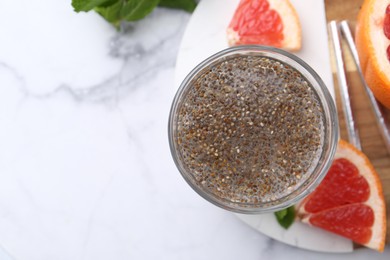 Photo of Glass of drink with chia seeds and grapefruit on white marble table, flat lay. Space for text