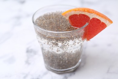 Photo of Glass of drink with chia seeds and grapefruit on white marble table, closeup