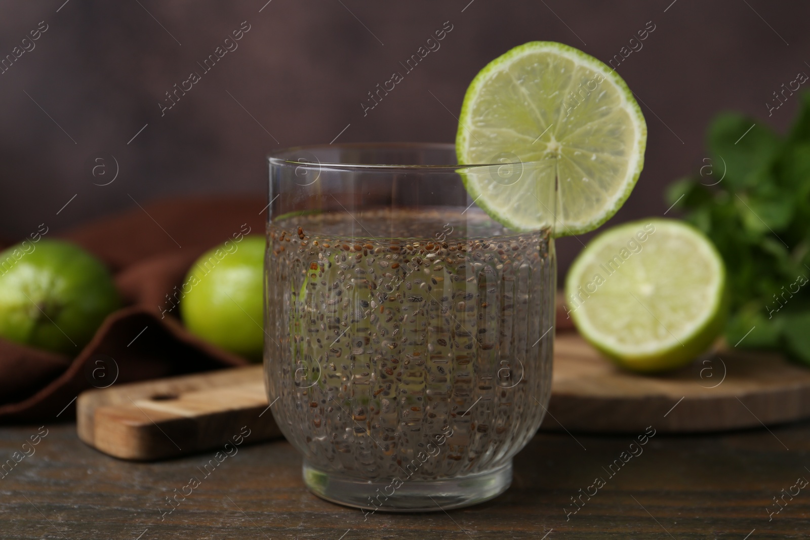 Photo of Glass of drink with chia seeds and lime on wooden table, closeup