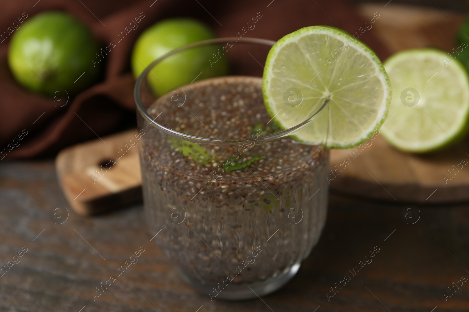 Photo of Glass of drink with chia seeds and lime on wooden table, closeup