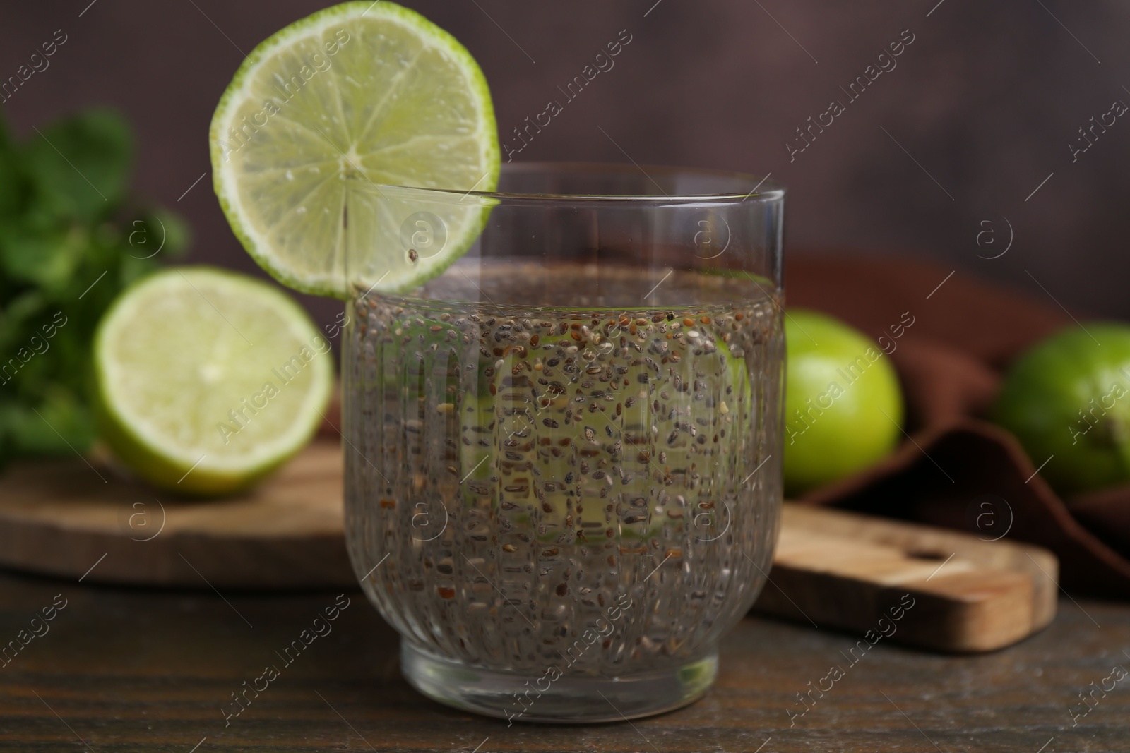 Photo of Glass of drink with chia seeds and lime on wooden table, closeup