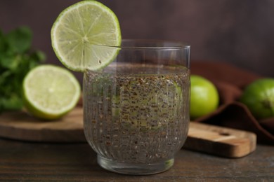 Photo of Glass of drink with chia seeds and lime on wooden table, closeup