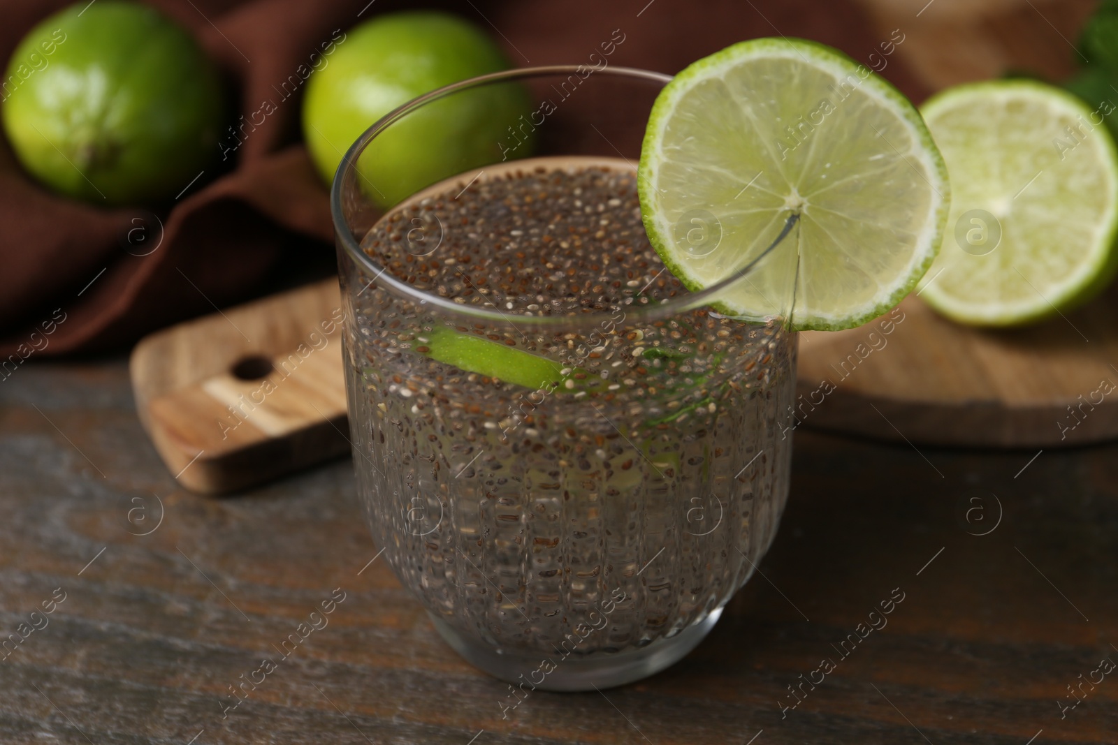 Photo of Glass of drink with chia seeds and lime on wooden table, closeup