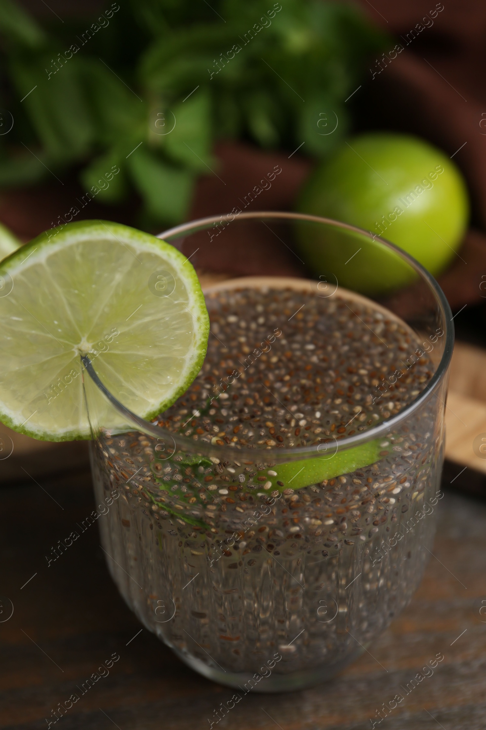 Photo of Glass of drink with chia seeds and lime on wooden table, closeup