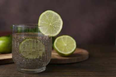 Photo of Glass of drink with chia seeds and lime on wooden table, closeup. Space for text