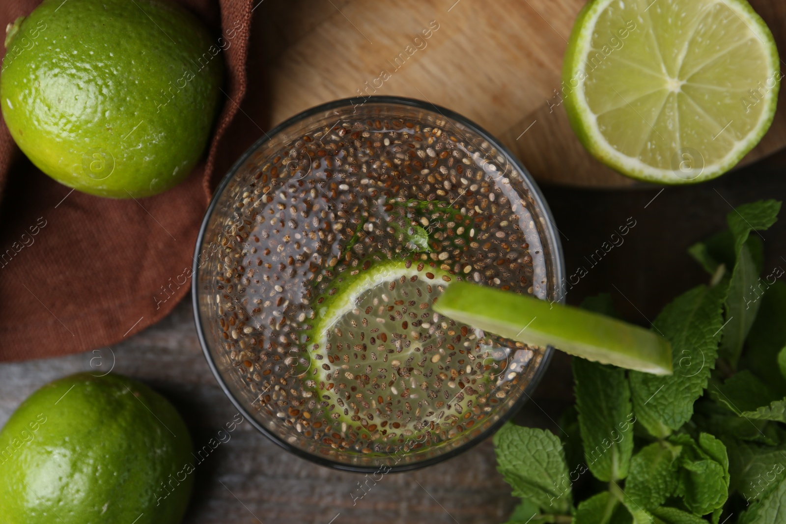 Photo of Glass of drink with chia seeds and lime on wooden table, flat lay