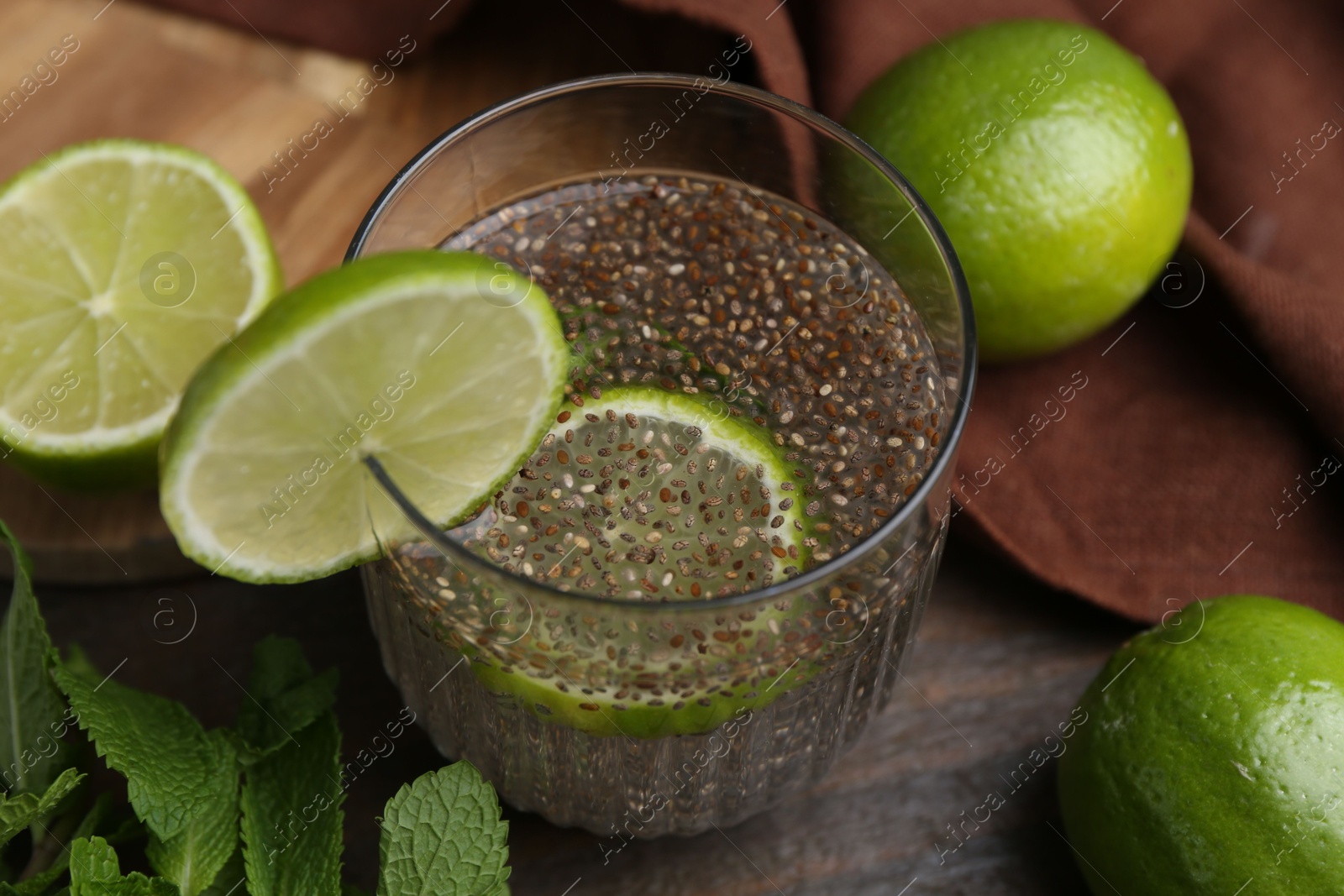 Photo of Glass of drink with chia seeds and lime on wooden table, closeup