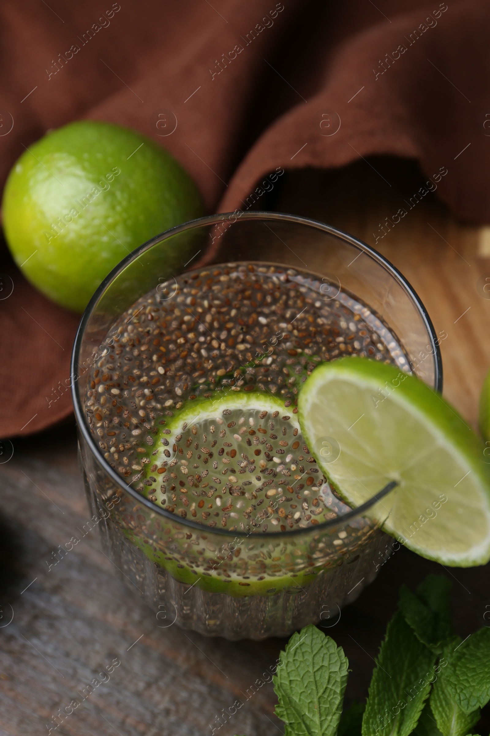 Photo of Glass of drink with chia seeds and lime on wooden table, closeup