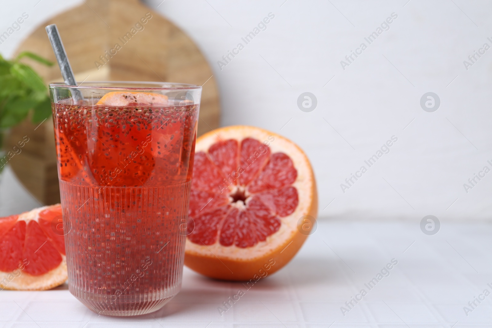 Glass of drink with chia seeds and grapefruit on white tiled table, closeup. Space for text Photo of Glass of drink with chia seeds and grapefruit on white tiled table, closeup. Space for text