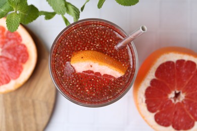 Photo of Glass of drink with chia seeds and grapefruit on white tiled table, flat lay