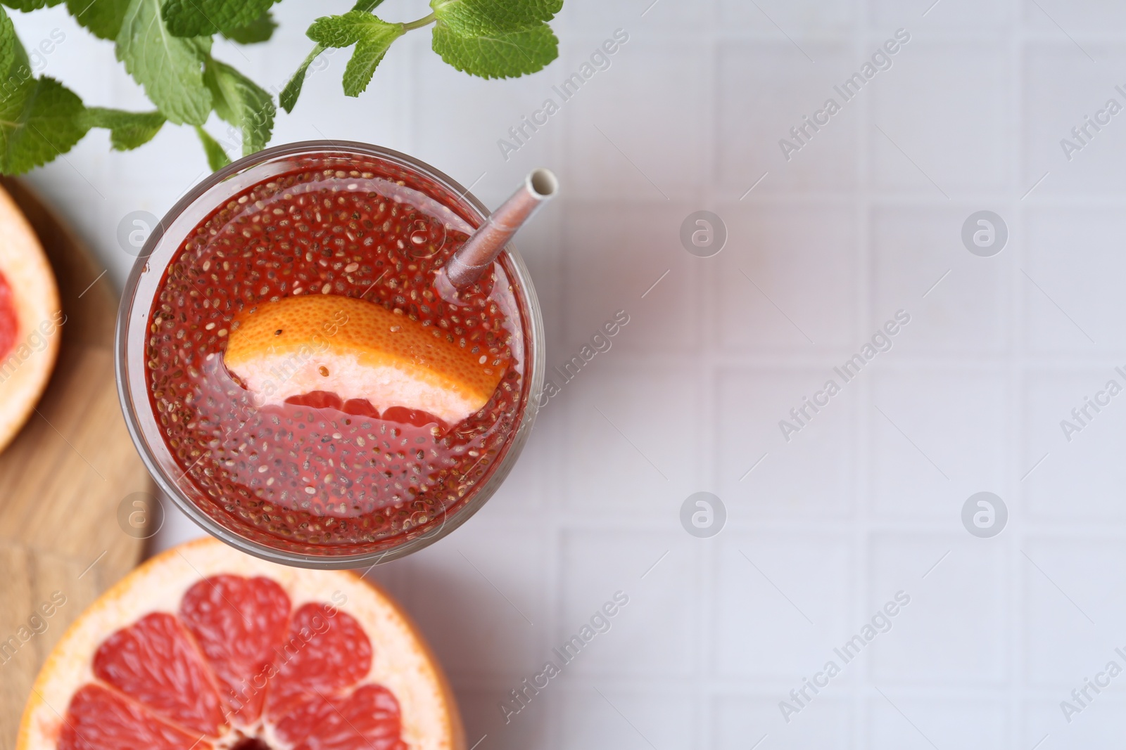 Glass of drink with chia seeds and grapefruit on white tiled table, flat lay. Space for text Photo of Glass of drink with chia seeds and grapefruit on white tiled table, flat lay. Space for text