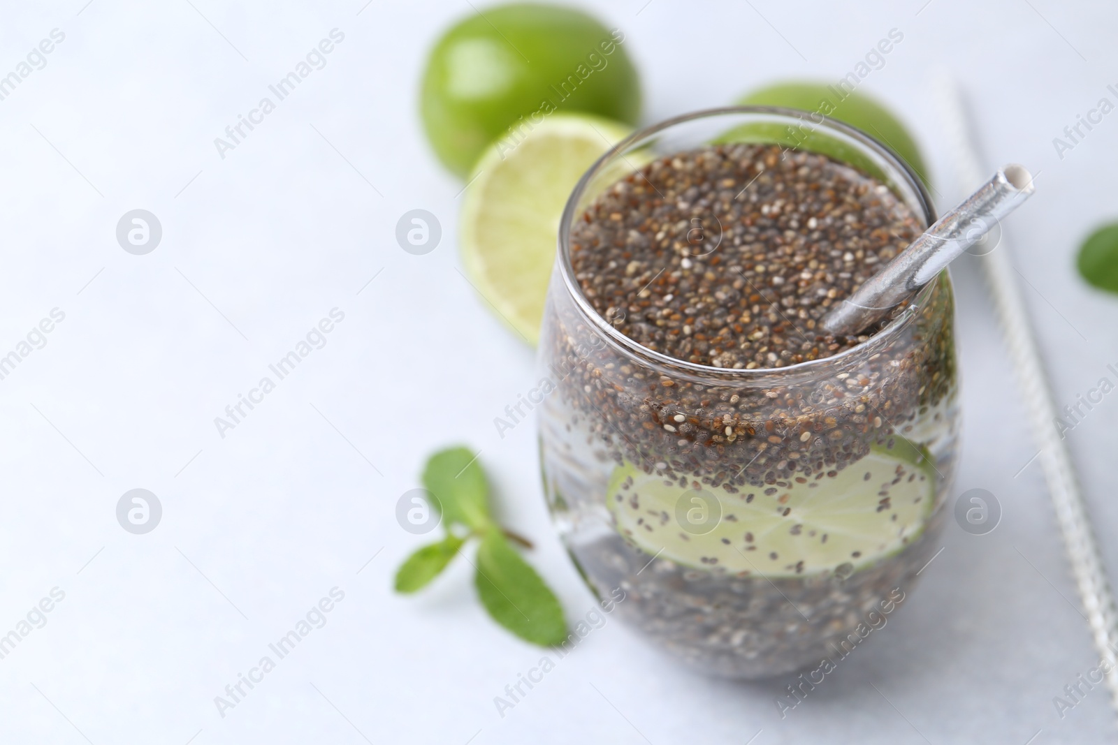 Photo of Glass of drink with chia seeds and lime on white table, closeup. Space for text