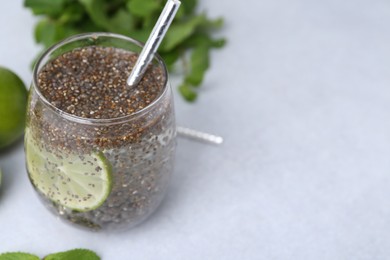 Photo of Glass of drink with chia seeds and lime on white table, closeup. Space for text