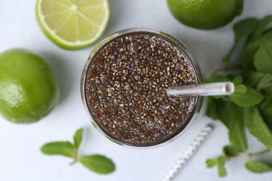 Photo of Glass of drink with chia seeds and lime on white table, flat lay