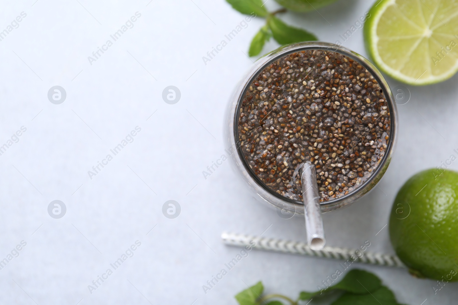 Photo of Glass of drink with chia seeds and lime on white table, flat lay. Space for text