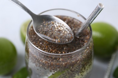 Photo of Glass of drink with chia seeds and lime on white table, closeup