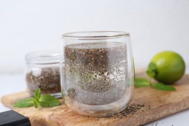 Photo of Glass of drink with chia seeds and lime on white table, closeup