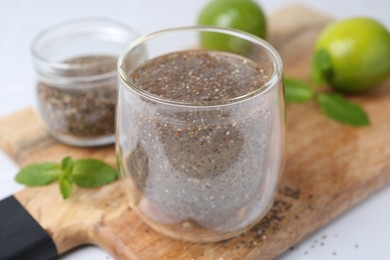 Photo of Glass of drink with chia seeds and lime on white table, closeup