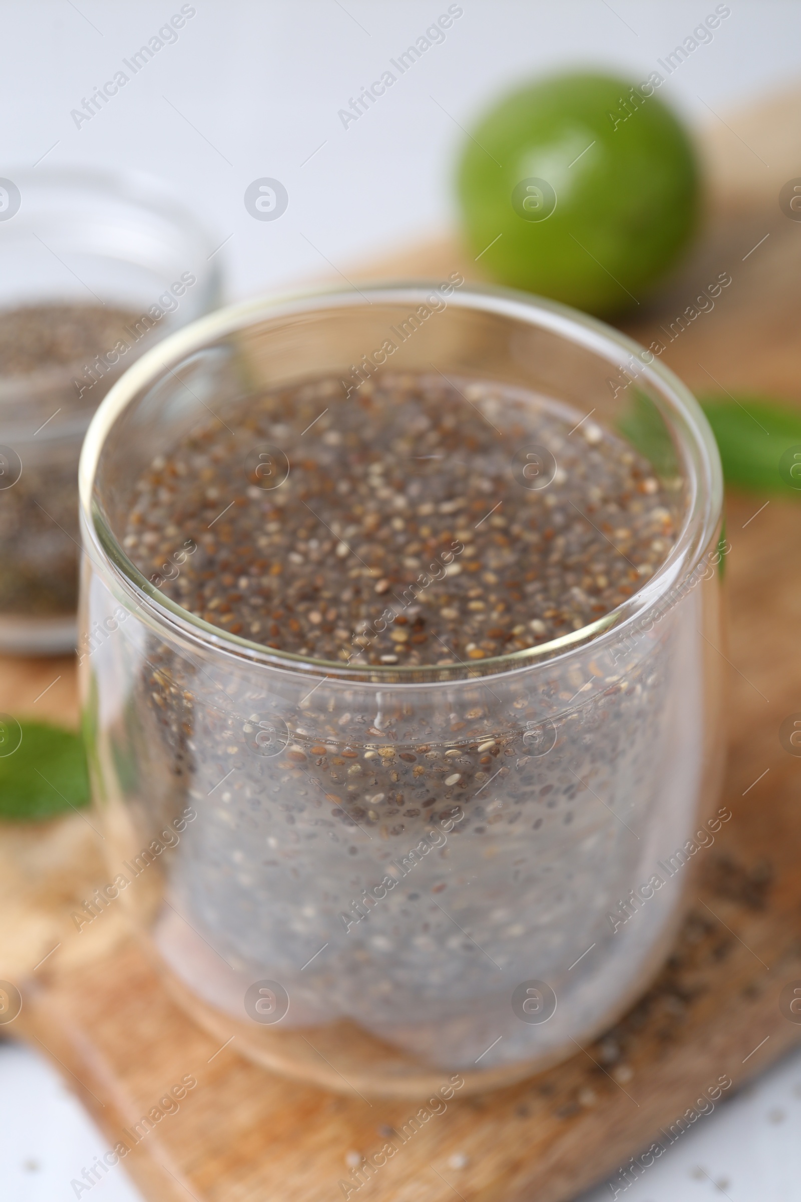 Photo of Glass of drink with chia seeds and lime on white table, closeup