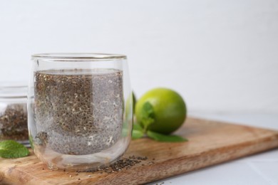 Photo of Glass of drink with chia seeds and lime on white table, space for text