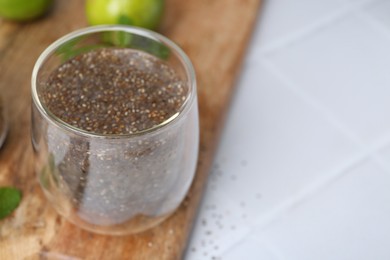 Photo of Glass of drink with chia seeds and lime on white tiled table, closeup. Space for text