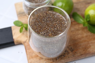 Photo of Glass of drink with chia seeds and lime on white table, closeup