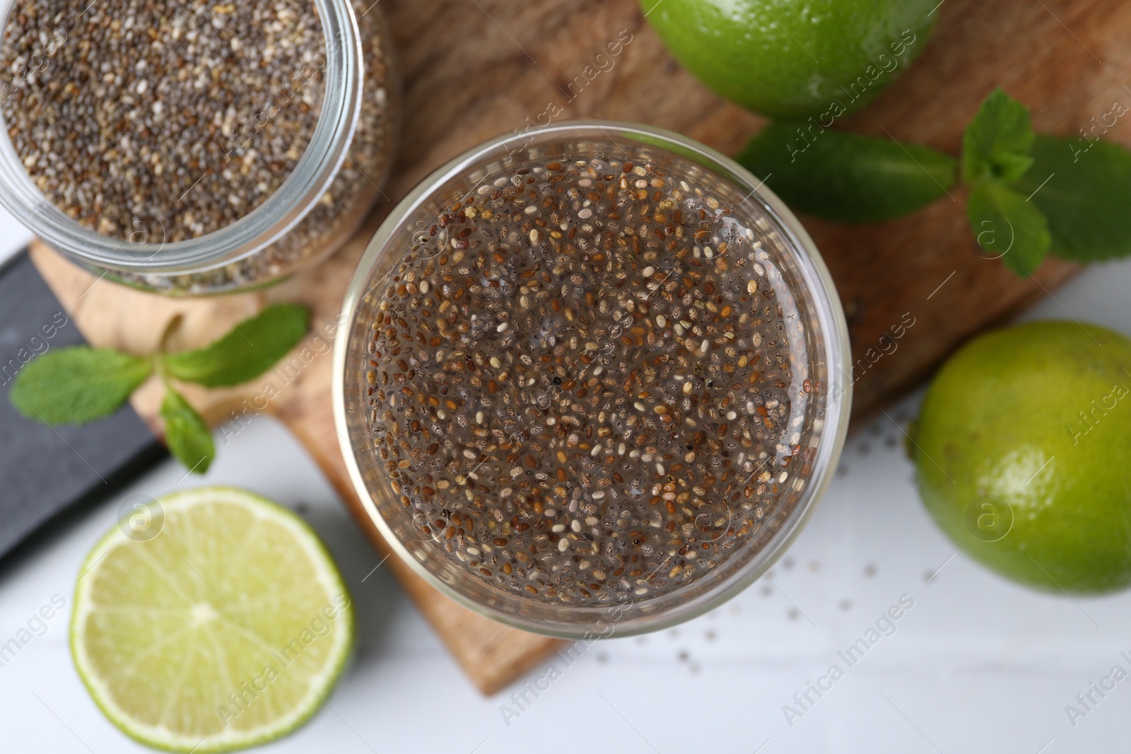 Photo of Glass of drink with chia seeds and lime on white tiled table, flat lay