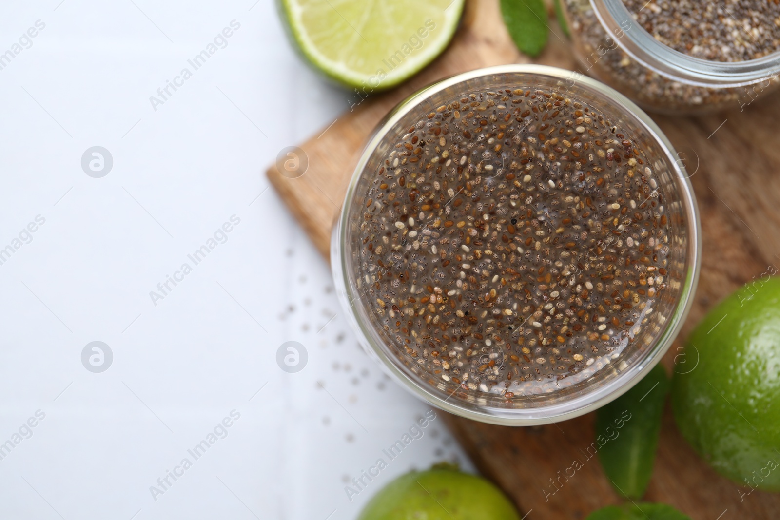 Photo of Glass of drink with chia seeds and lime on white tiled table, flat lay. Space for text