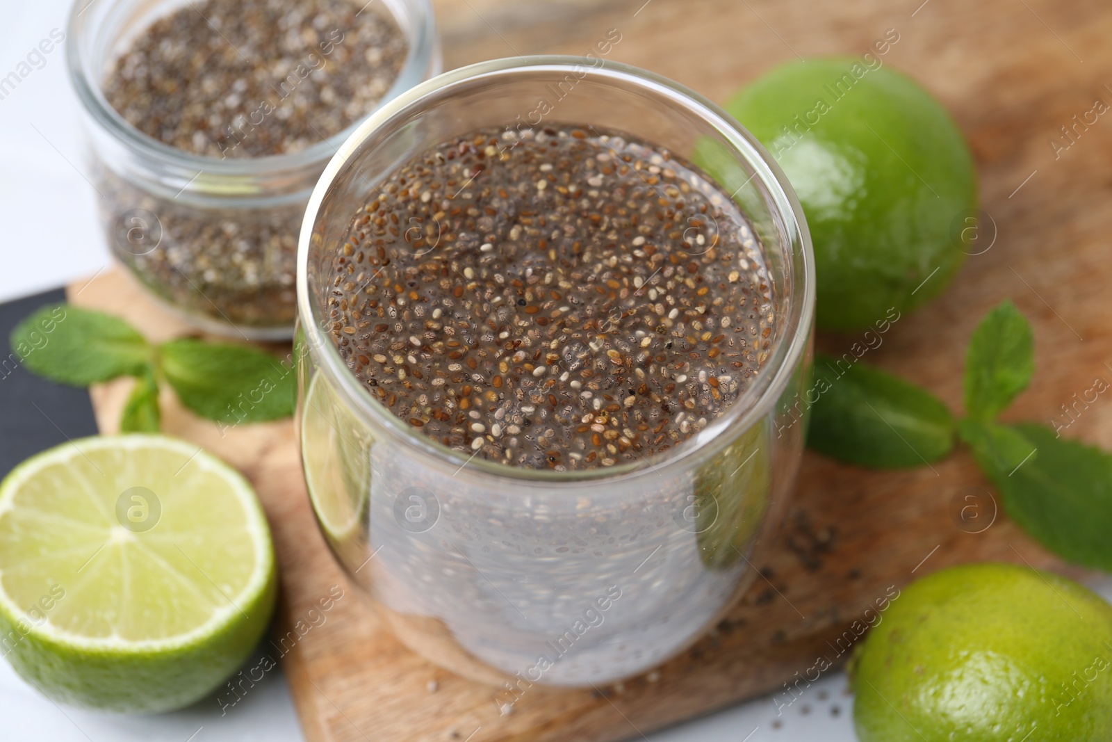 Photo of Glass of drink with chia seeds and lime on white table, closeup