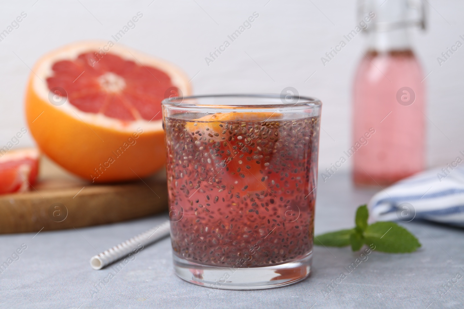 Photo of Glass of drink with chia seeds and grapefruit on grey table, closeup