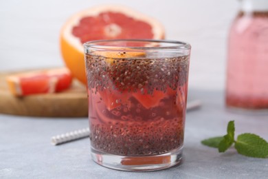 Photo of Glass of drink with chia seeds and grapefruit on grey table, closeup