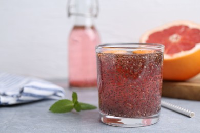 Photo of Glass of drink with chia seeds and grapefruit on grey table, closeup