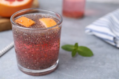 Photo of Glass of drink with chia seeds and grapefruit on grey table, closeup