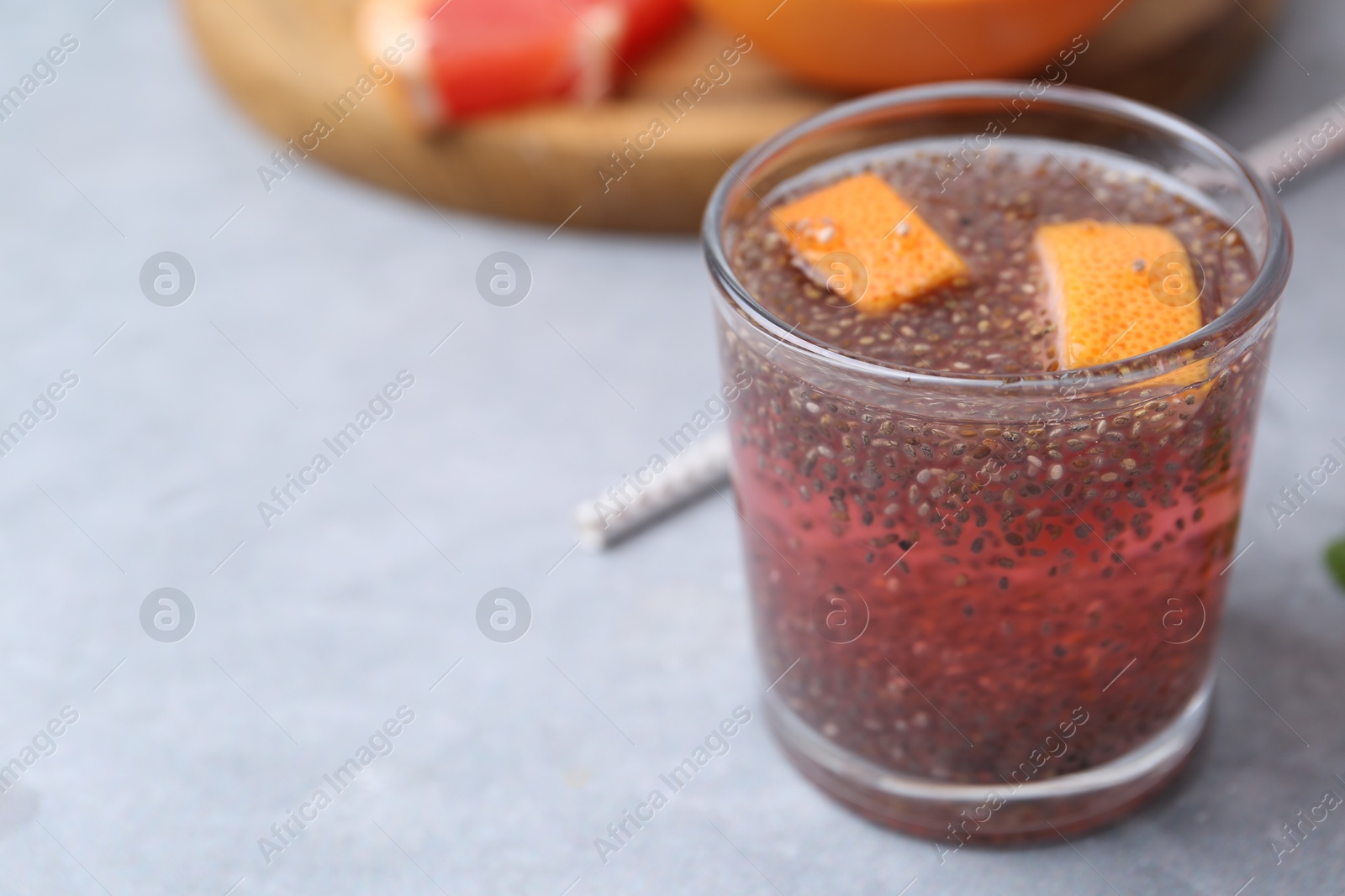 Photo of Glass of drink with chia seeds and grapefruit on grey table, closeup. Space for text