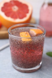 Photo of Glass of drink with chia seeds and grapefruit on grey table, closeup