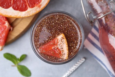 Photo of Glass of drink with chia seeds and grapefruit on grey table, flat lay