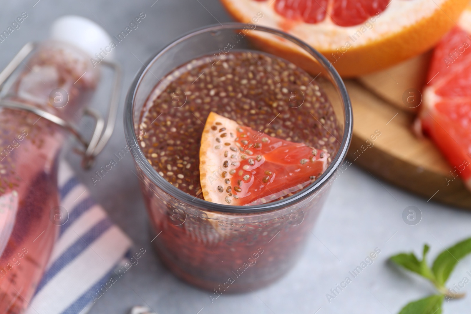 Photo of Glass of drink with chia seeds and grapefruit on grey table, closeup