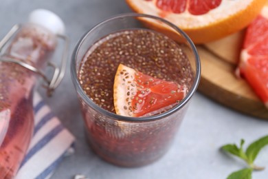 Photo of Glass of drink with chia seeds and grapefruit on grey table, closeup