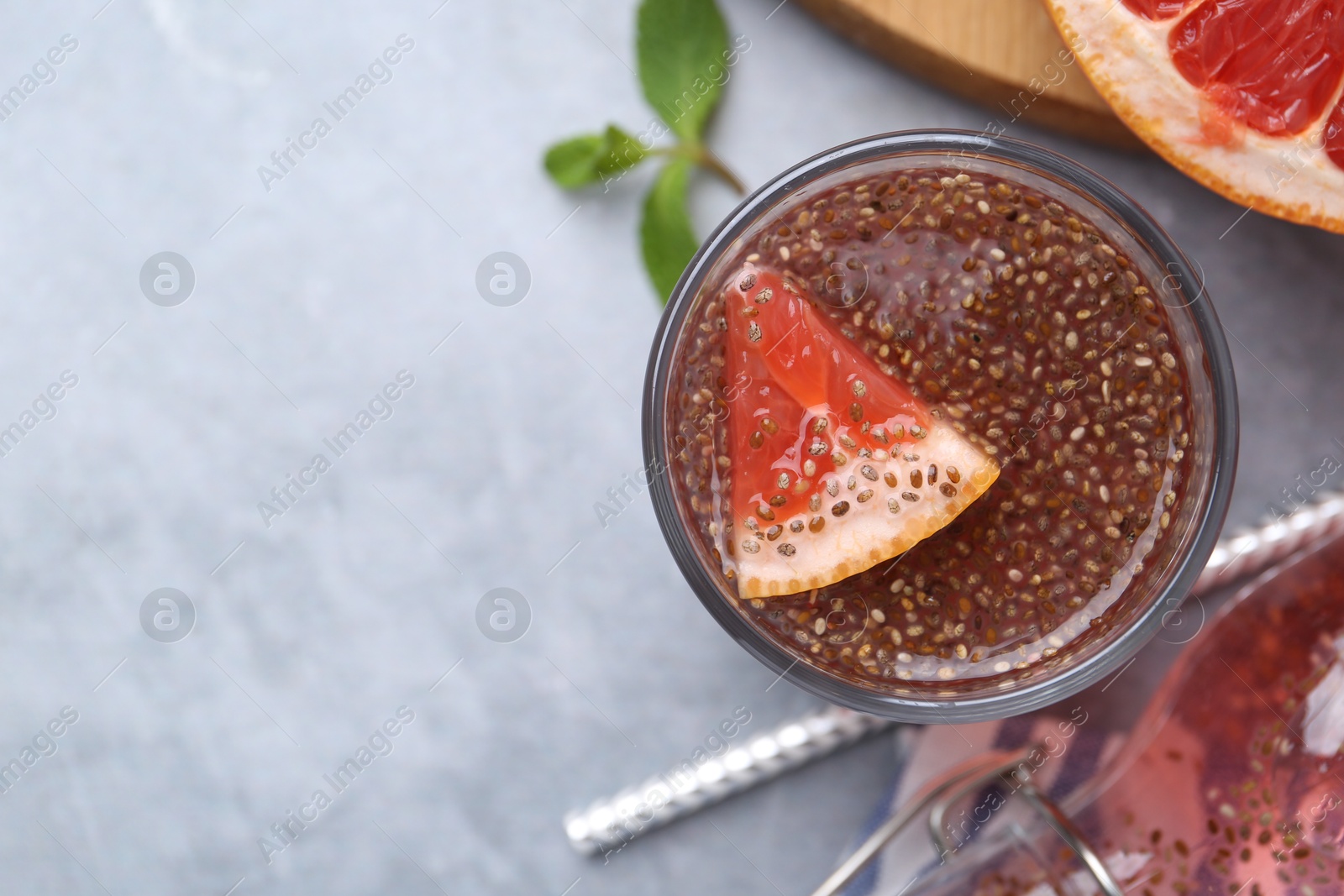 Photo of Glass of drink with chia seeds and grapefruit on grey table, flat lay. Space for text