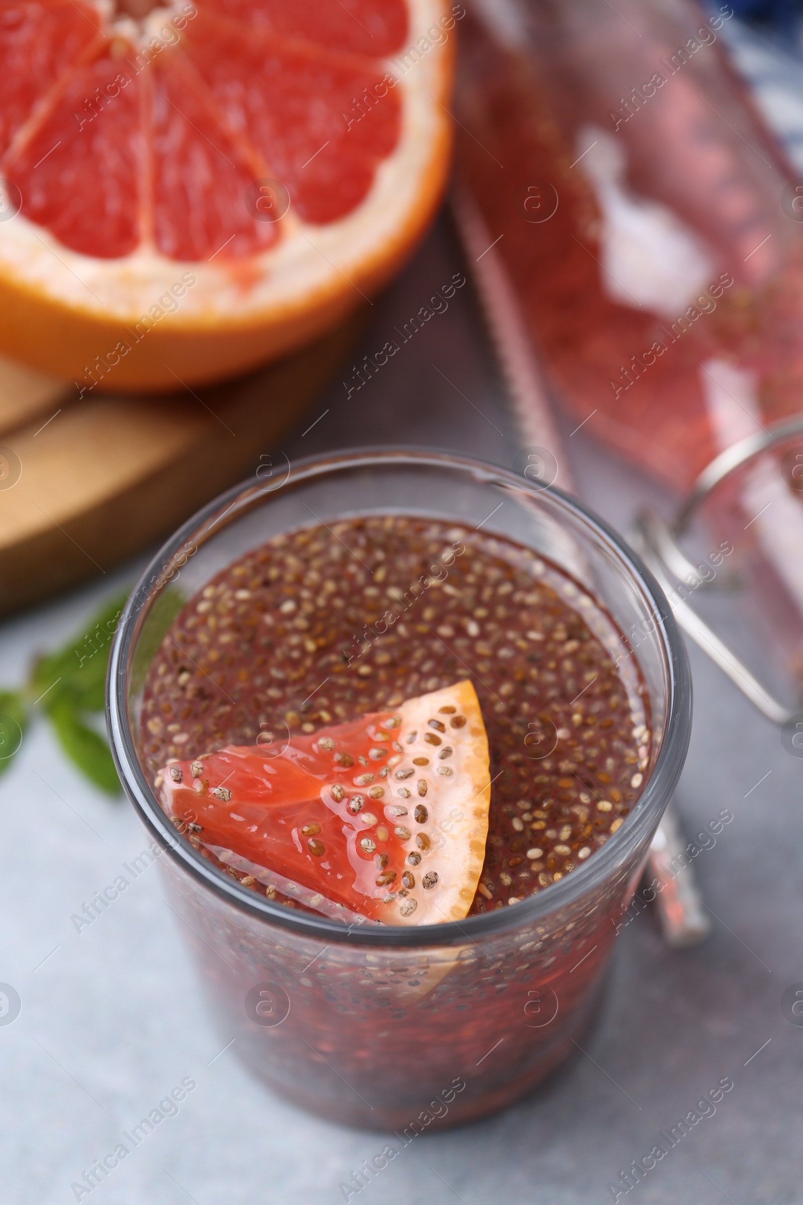 Photo of Glass of drink with chia seeds and grapefruit on grey table, closeup