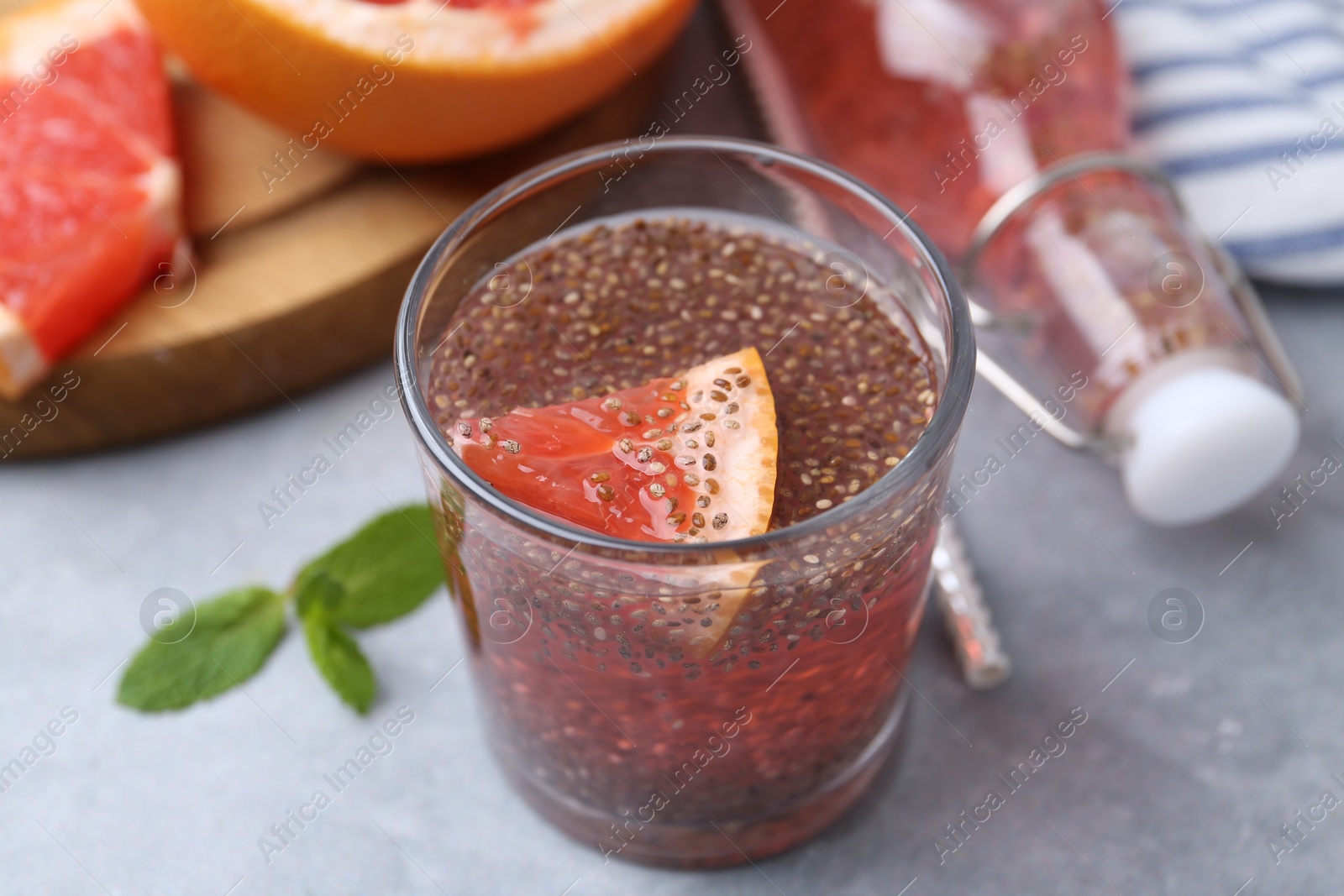 Photo of Glass of drink with chia seeds and grapefruit on grey table, closeup