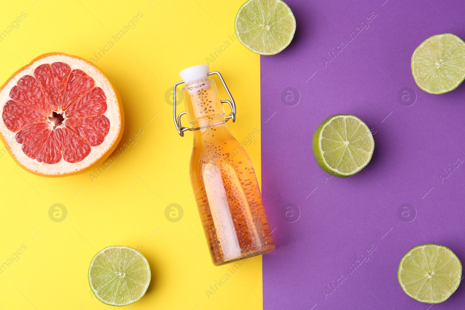 Photo of Bottle of drink with chia seeds, limes and grapefruit on color background, flat lay