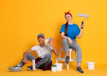 Photo of Professional decorator. Man and woman with different tools on orange background