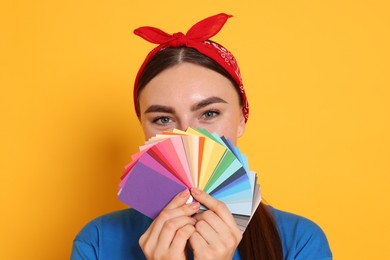 Photo of Portrait of young decorator with color palettes on orange background