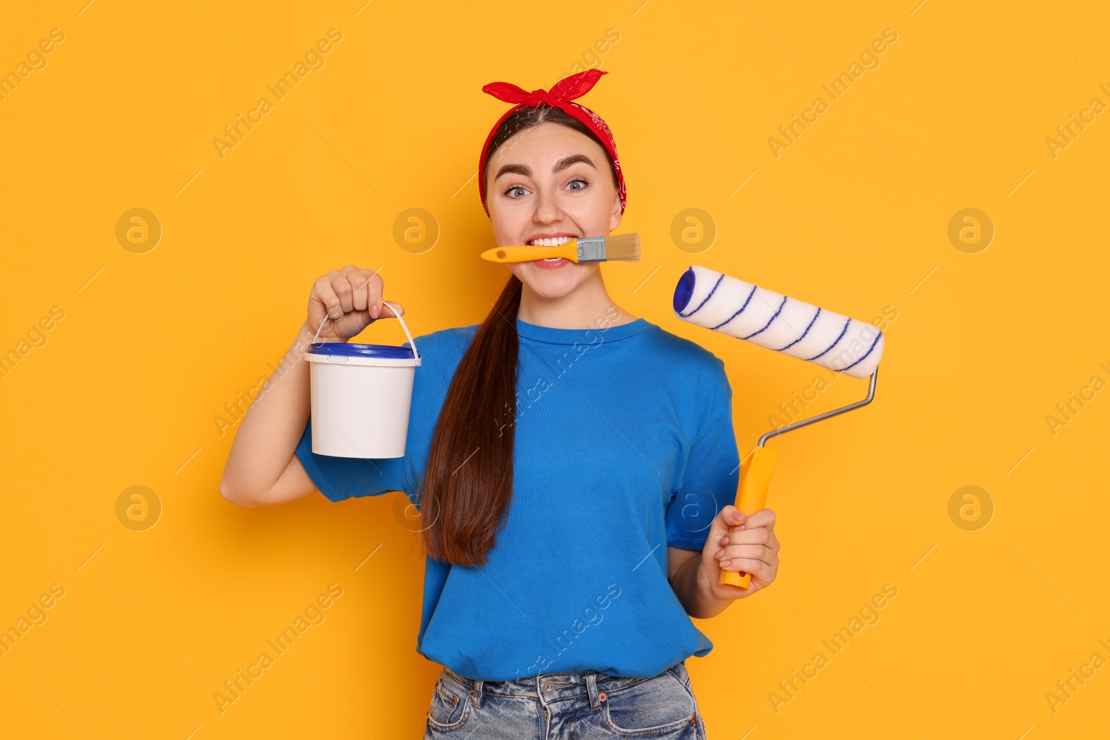 Photo of Portrait of young decorator with different tools on orange background