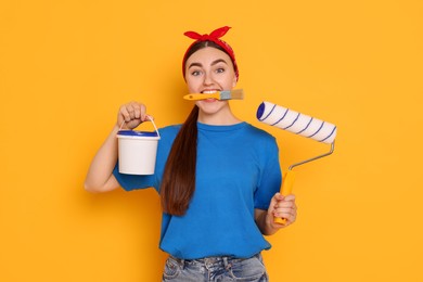 Portrait of young decorator with different tools on orange background