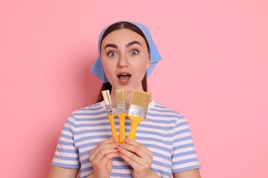 Photo of Portrait of young decorator with brushes on pink background