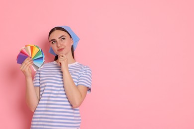 Portrait of young decorator with color palettes on pink background, space for text