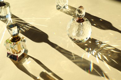 Photo of Many perfume bottles casting beautiful shadows on beige background