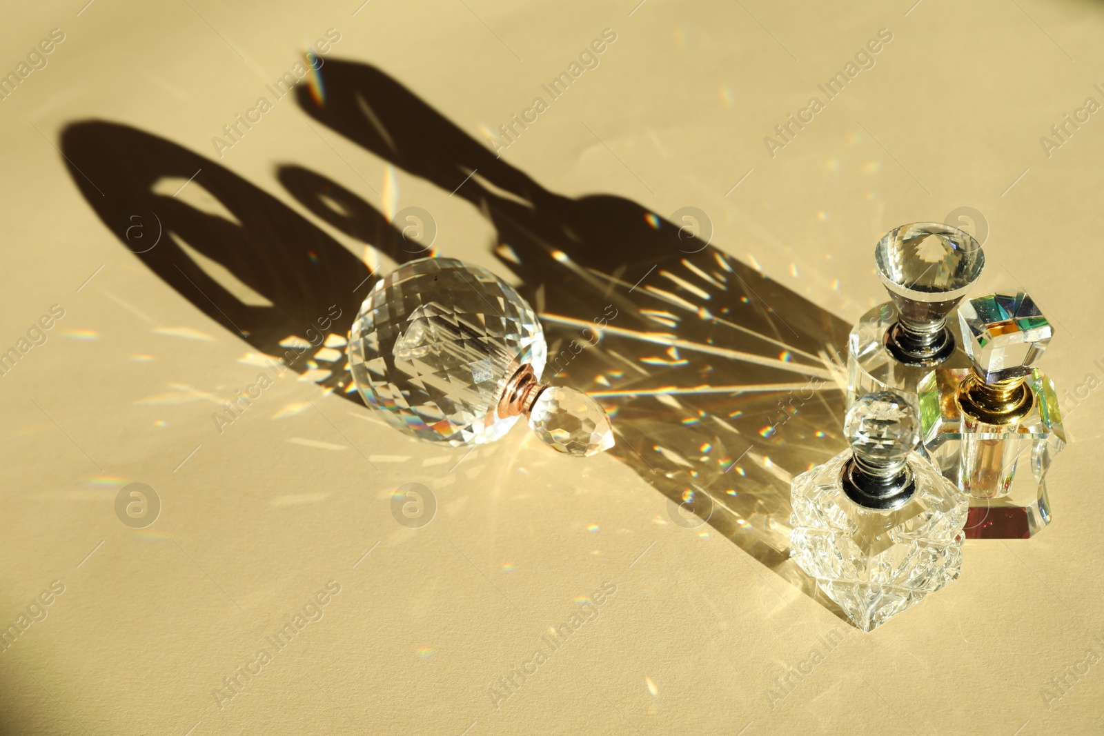 Photo of Many perfume bottles casting beautiful shadows on beige background